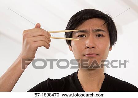 Young Asian man holding chopsticks View Large Photo Image Stock Image - Young Asian man holding chopsticks. Fotosearch