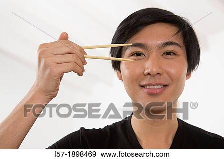 Stock Photo - Young Asian man holding chopsticks. Fotosearch