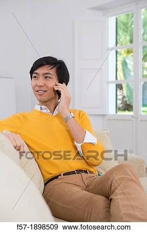 Young Asian man talking on his smartphone View Large Photo Image Stock Photo - Young Asian man talking on his smartphone. Fotosearch