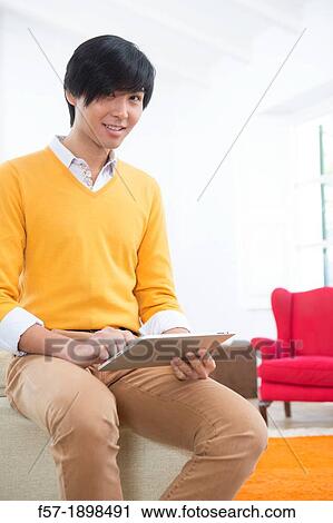 Young Asian man using his Tablet computer View Large Photo Image Stock Image - Young Asian man using his Tablet computer. Fotosearch