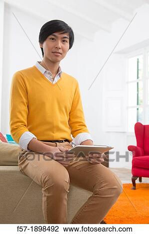 Young Asian man using his Tablet computer View Large Photo Image Stock Image - Young Asian man using his Tablet computer. Fotosearch