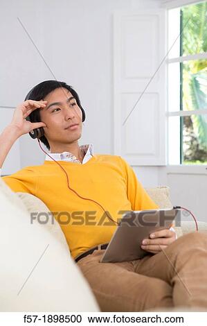 Stock Image - Young Asian man using his Tablet computer. Fotosearch