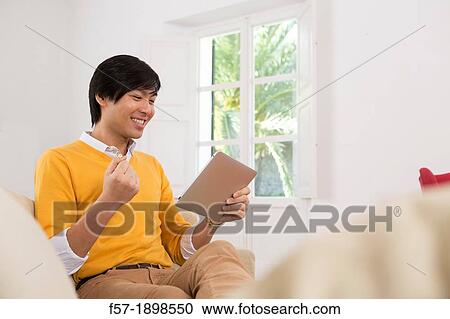 Young Asian man using his Tablet computer View Large Photo Image Stock Image - Young Asian man using his Tablet computer. Fotosearch