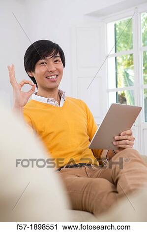 Young Asian man using his Tablet computer View Large Photo Image Stock Image - Young Asian man using his Tablet computer. Fotosearch