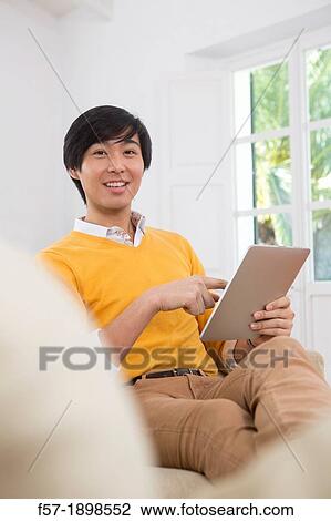 Young Asian man using his Tablet computer View Large Photo Image Stock Image - Young Asian man using his Tablet computer. Fotosearch