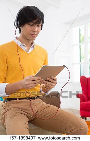 Young Asian man using his Tablet computer View Large Photo Image Stock Photo - Young Asian man using his Tablet computer. Fotosearch