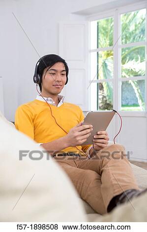 Young Asian man using his Tablet computer View Large Photo Image Stock Photo - Young Asian man using his Tablet computer. Fotosearch