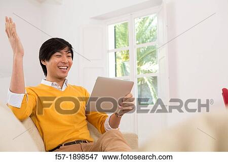 Young Asian man using his Tablet computer View Large Photo Image Stock Photo - Young Asian man using his Tablet computer. Fotosearch