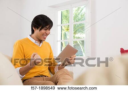 Young Asian man using his Tablet computer View Large Photo Image Stock Photo - Young Asian man using his Tablet computer. Fotosearch