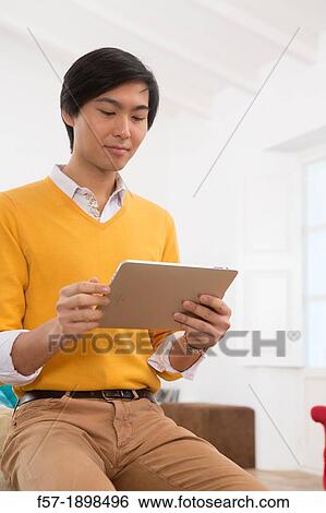 Young Asian man using his Tablet computer View Large Photo Image Stock Photograph - Young Asian man using his Tablet computer. Fotosearch