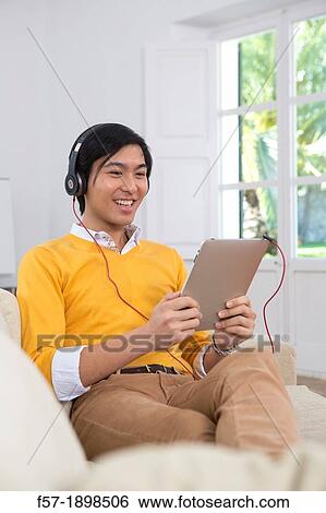 Young Asian man using his Tablet computer View Large Photo Image Stock Photograph - Young Asian man using his Tablet computer. Fotosearch