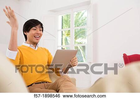 Young Asian man using his Tablet computer View Large Photo Image Stock Photograph - Young Asian man using his Tablet computer. Fotosearch