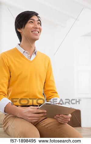 Young Asian man using his Tablet computer View Large Photo Image Stock Photography - Young Asian man using his Tablet computer. Fotosearch