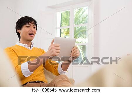 Young Asian man using his Tablet computer View Large Photo Image Stock Photography - Young Asian man using his Tablet computer. Fotosearch