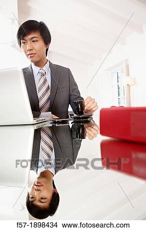 Young Asian man working on his laptop computer View Large Photo Image Picture - Young Asian man working on his laptop computer. Fotosearch