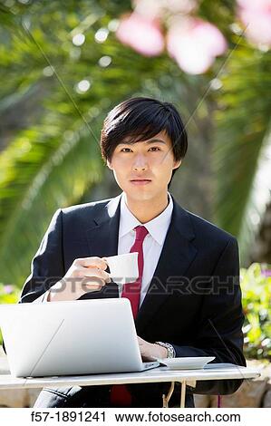 Young Asian man working on his laptop computer outside View Large Photo Image Stock Image - Young Asian man working on his laptop computer outside. Fotosearch