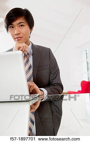 Young Asian man working on his laptop computer View Large Photo Image Stock Image - Young Asian man working on his laptop computer. Fotosearch