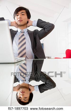 Stock Image - Young Asian man working on his laptop computer. Fotosearch