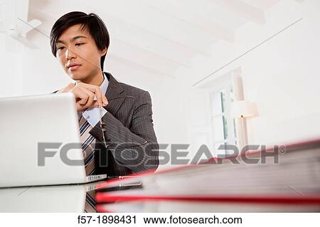 Young Asian man working on his laptop computer View Large Photo Image Stock Image - Young Asian man working on his laptop computer. Fotosearch