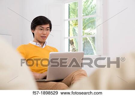 Young Asian man working on his laptop computer View Large Photo Image Stock Photo - Young Asian man working on his laptop computer. Fotosearch