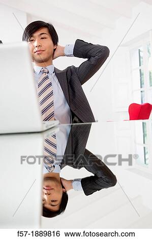 Young Asian man working on his laptop computer View Large Photo Image Stock Photograph - Young Asian man working on his laptop computer. Fotosearch