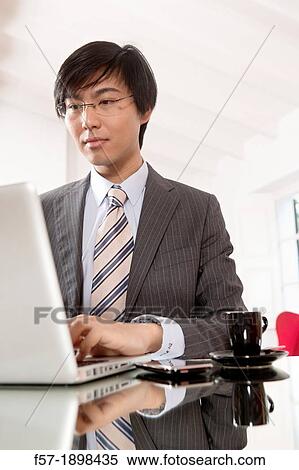 Young Asian man working on his laptop computer View Large Photo Image Stock Photography - Young Asian man working on his laptop computer. Fotosearch
