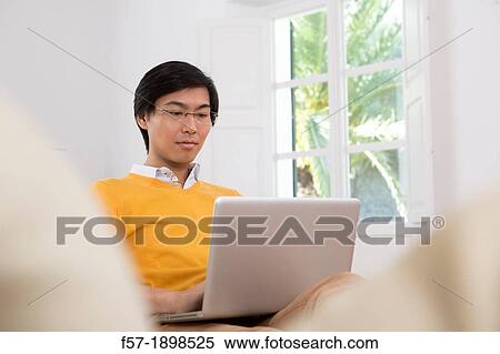 Young Asian man working on his laptop computer View Large Photo Image Stock Photography - Young Asian man working on his laptop computer. Fotosearch