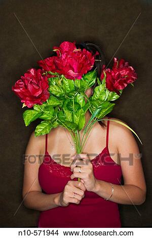 Young Asian woman holding a bouquet of flowers in front of her face View Large Photo Image Picture - Young Asian woman holding a bouquet of flowers in front of her face. Fotosearch