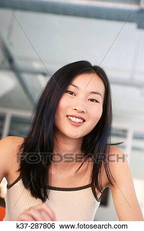 Young Asian woman in contemporary loft or office with personal digital assistant on table View Large Photo Image Stock Photograph - Young Asian woman in contemporary loft or office with personal digital assistant on table. Fotosearch