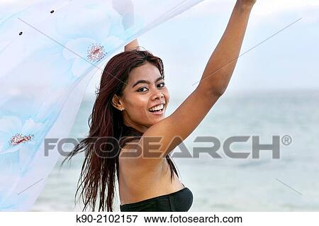 Stock Photo - Young asian woman playing with a tissue that is blowing in the wind, Bali, Indonesia, Southeast Asia.. Fotosearch