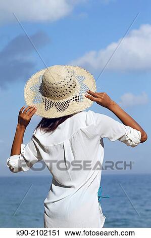 Young asian woman seen from behind, wearing a hat and holding it with both hands, Bali, Indonesia, Southeast Asia. View Large Photo Image Stock Image - Young asian woman seen from behind, wearing a hat and holding it with both hands, Bali, Indonesia, Southeast Asia.. Fotosearch