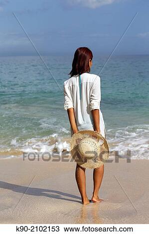 Young asian woman seen from behind, holding a hat and standing at the beach, Bali, Indonesia, Southeast Asia. View Large Photo Image Stock Image - Young asian woman seen from behind, holding a hat and standing at the beach, Bali, Indonesia, Southeast Asia.. Fotosearch