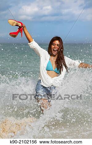 Young asian woman seen from front with splashing water, holding her red high heals high in the air and crying, Bali, Indonesia, Southeast Asia. View Large Photo Image Stock Photograph - Young asian woman seen from front with splashing water, holding her red high heals high in the air and crying, Bali, Indonesia, Southeast Asia.. Fotosearch