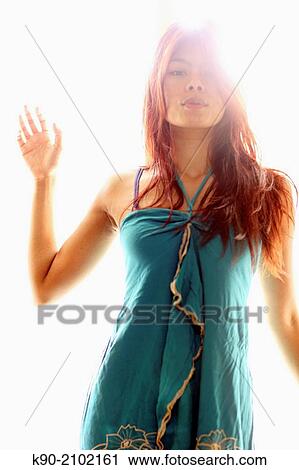 Stock Image - Young asian woman standing against the light, Bali, Indonesia, Southeast Asia.. Fotosearch