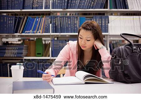 Young Asian woman studying from a textbook in a library. View Large Photo Image Stock Photo - Young Asian woman studying from a textbook in a library.. Fotosearch