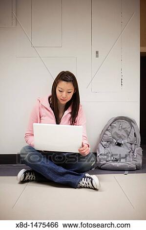 Young Asian woman using her laptop computer while sitting on floor in school hallway. View Large Photo Image Stock Photograph - Young Asian woman using her laptop computer while sitting on floor in school hallway.. Fotosearch