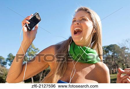 young attractive 50 year old woman listening to music on cell phone smiling outdoors still beautiful even in middle age with sunlight in her hair and great smile. View Large Photo Image Stock Photograph - young attractive 50 year old woman listening to music on cell phone smiling outdoors still beautiful even in middle age with sunlight in her hair and great smile.. Fotosearch