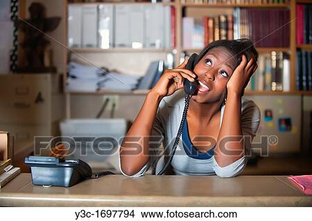 Young attractive black girl having private phone conversation while working as ofice clerk View Large Photo Image Picture - Young attractive black girl having private phone conversation while working as ofice clerk. Fotosearch