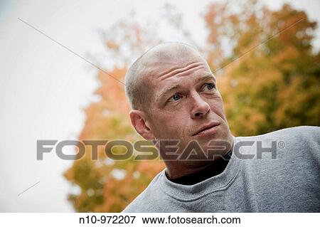 Stock Photo - Young bald man near trees changing color. Fotosearch