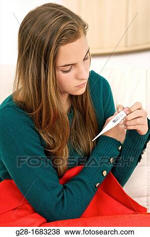 Stock Photo - young beautiful teenage girl, holding a medical thermometer for temperature. Fotosearch