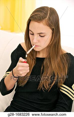 Young beautiful teenage girl lighting a joint with a red lighter View Large Photo Image Stock Photograph - Young beautiful teenage girl lighting a joint with a red lighter. Fotosearch