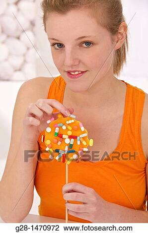 Young beautiful woman about to take a pill from an orange lollipop View Large Photo Image Stock Image - Young beautiful woman about to take a pill from an orange lollipop. Fotosearch