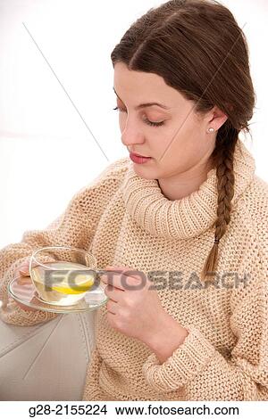 young beautiful woman holding a glass cup of herb tea with a slice of lemon, suffering from a cold View Large Photo Image Picture - young beautiful woman holding a glass cup of herb tea with a slice of lemon, suffering from a cold. Fotosearch