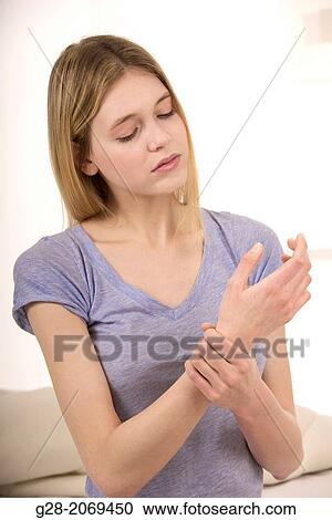 Young beautiful woman holding her stiff painful wrist View Large Photo Image Stock Image - Young beautiful woman holding her stiff painful wrist. Fotosearch