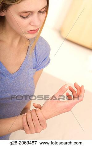 Stock Photo - Young beautiful woman holding her stiff painful wrist. Fotosearch