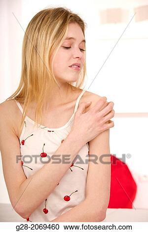 Stock Image - Young beautiful woman holding her painful shoulder. Fotosearch