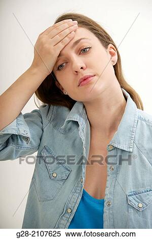 Young beautiful woman in a blue jeans shirt, with her hand on her forehead for headache pain View Large Photo Image Stock Photography - Young beautiful woman in a blue jeans shirt, with her hand on her forehead for headache pain. Fotosearch