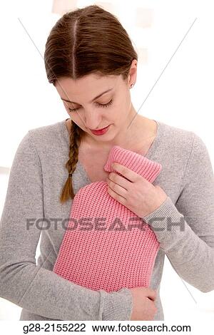 Young beautiful woman in grey holding a pink hot water bottle for stomach ache relief View Large Photo Image Stock Image - Young beautiful woman in grey holding a pink hot water bottle for stomach ache relief. Fotosearch