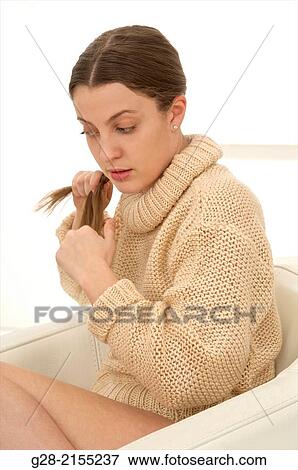 Stock Photo - Young beautiful woman in grey plaiting her long hair. Fotosearch