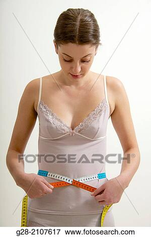 Young beautiful woman in pink underwear, measuring her waistline with a measuring tape View Large Photo Image Stock Photo - Young beautiful woman in pink underwear, measuring her waistline with a measuring tape. Fotosearch